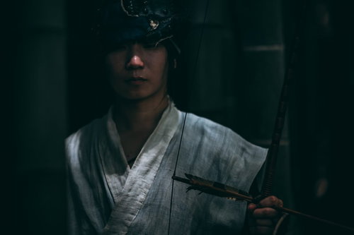 暗がりで大弓を持ち静かに佇む追いはぎの男性