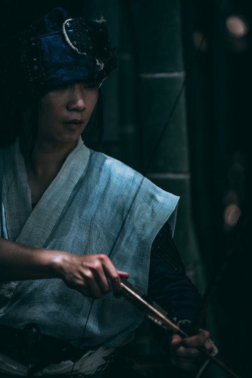 伏し目がちに大弓を引く野盗男性、時代劇キャラクター
