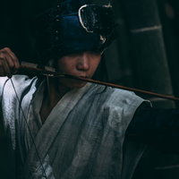 暗がりで弓を引く野盗の男性が奇襲攻撃を仕掛ける緊迫した瞬間の写真