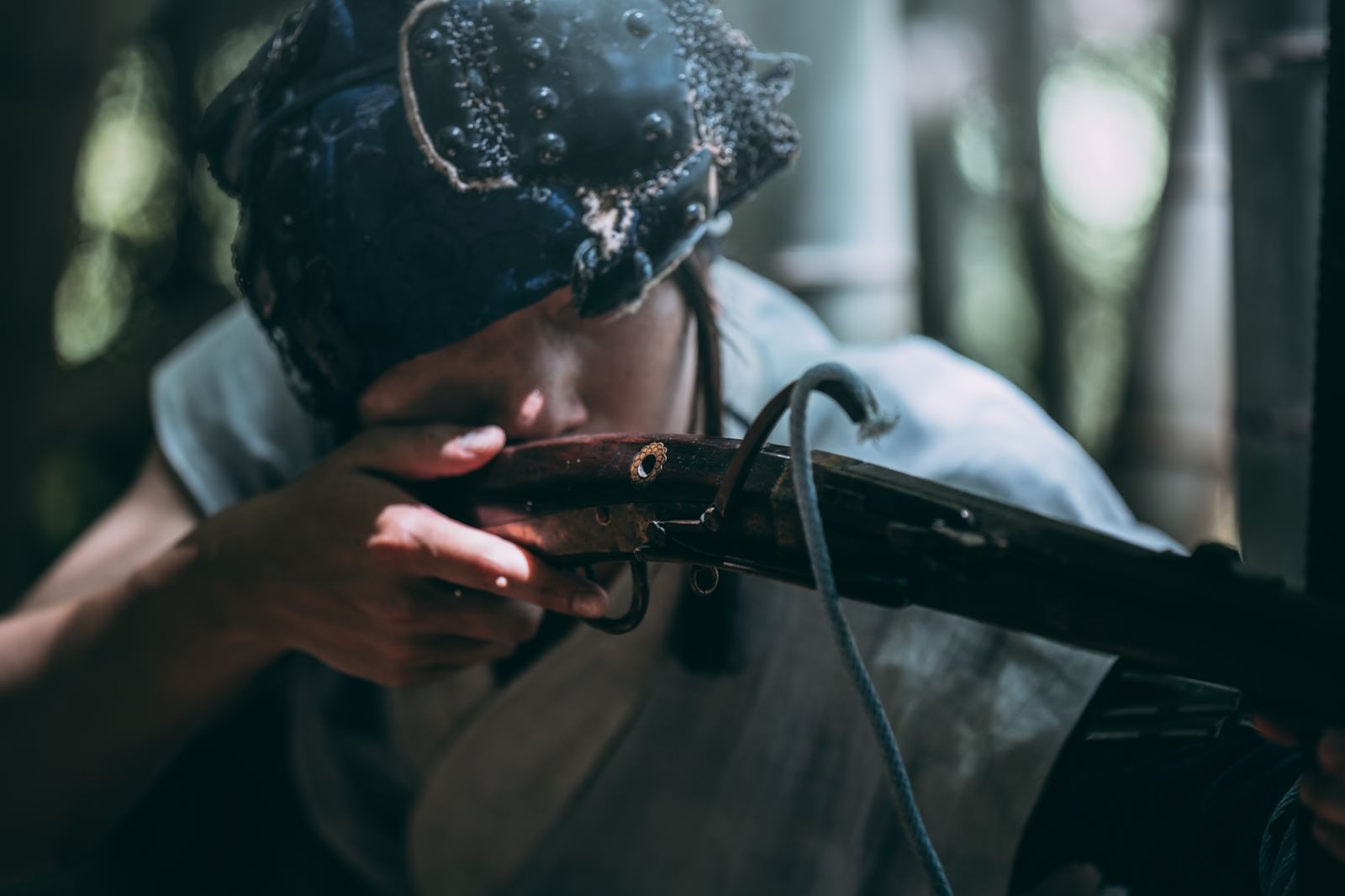 竹林の中で火縄銃を構えて狙いを定める野盗の男性［モデル：まーこ］