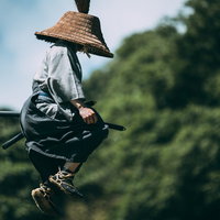 飛び上がる用心棒の麻混着姿と藁編み笠、アクション決めポーズの写真