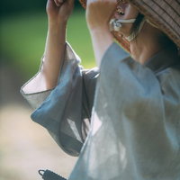 両手で笠を持ち上げ前方を確認する侍の姿勢の写真