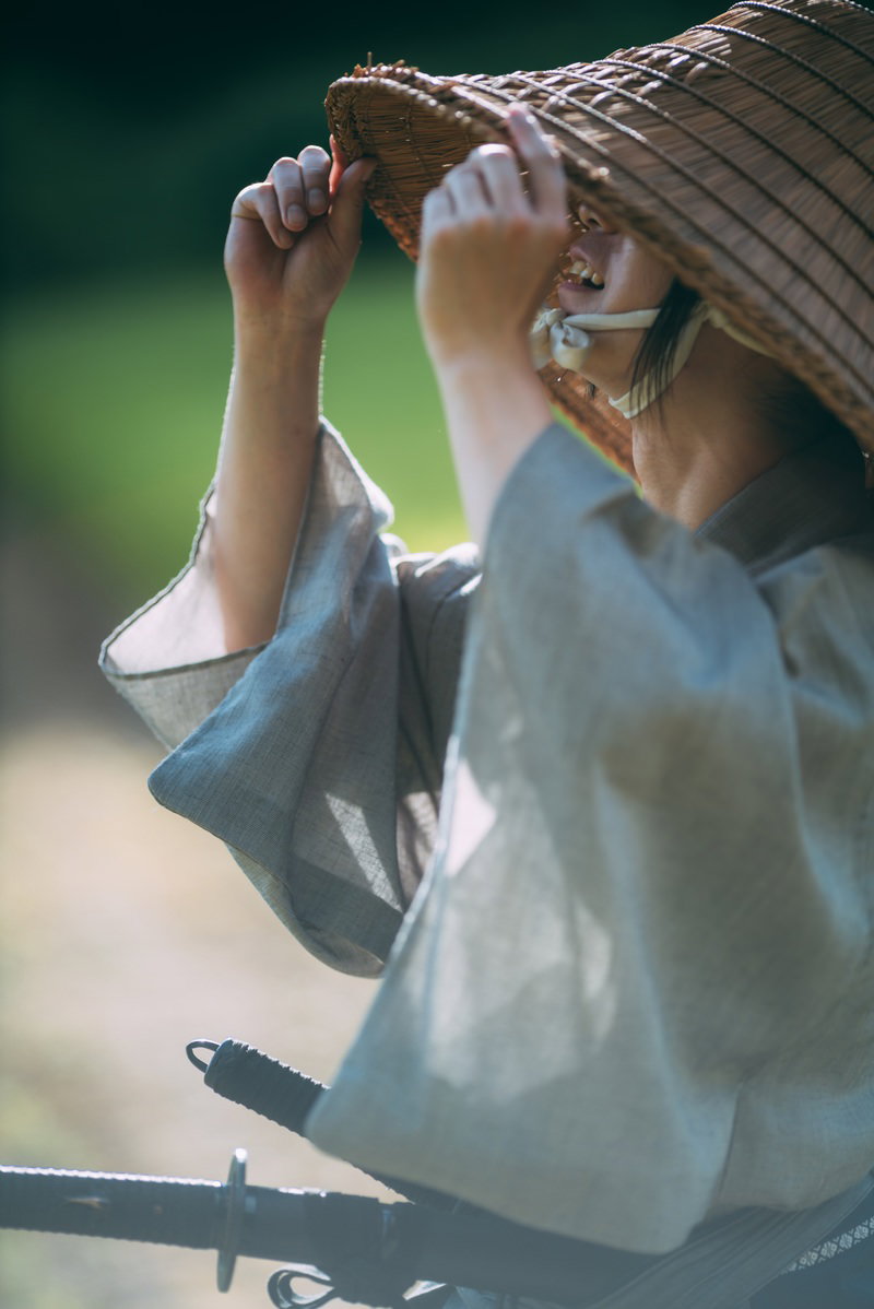 両手で笠を持ち上げて前方を見つめる、袴姿の侍男性［モデル：まーこ］