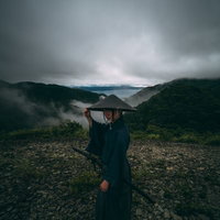 怪しい雲行きの山道で笠を掲げる侍の旅路と時代物語の写真