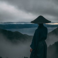 迫りくる灰色の雲と御霊櫃峠の侍の後ろ姿と山並みの写真
