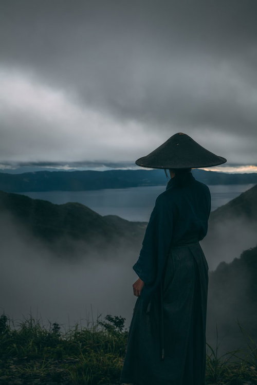 迫りくる灰色の雲と御霊櫃峠の侍の後ろ姿と山並み