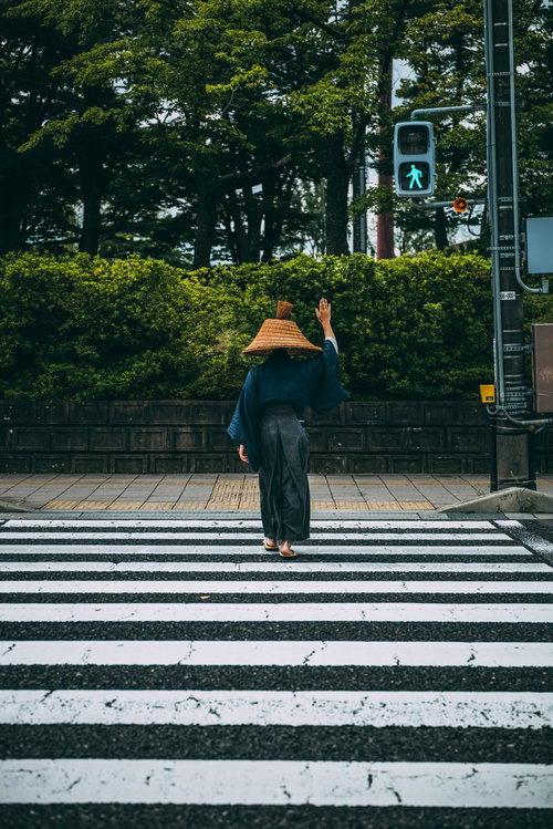 手を上げて横断歩道を渡る網代笠姿の侍用心棒