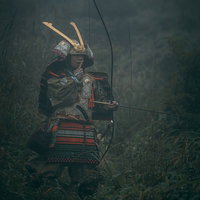 指を舐める大鎧を纏った侍のポーズ 森で弓を構える武士の写真