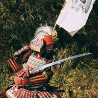 白い髑髏の旗を掲げて甲冑を纏い応戦する武士の写真