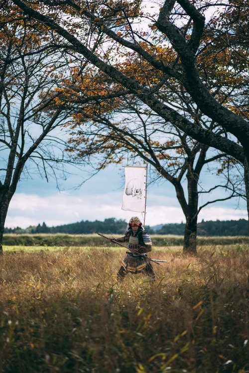 草むらで長槍を構える黒い当世具足の侍、指物付き