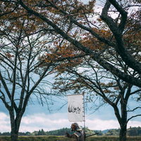 草原で棍棒を構える指物を立てた甲冑姿の武士の写真