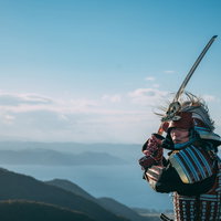 山々を背景に上段の構えをとる甲冑姿の武士の写真