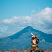 磐梯山を背に猪苗代湖の中州で二刀流をキメる大鎧武士の写真