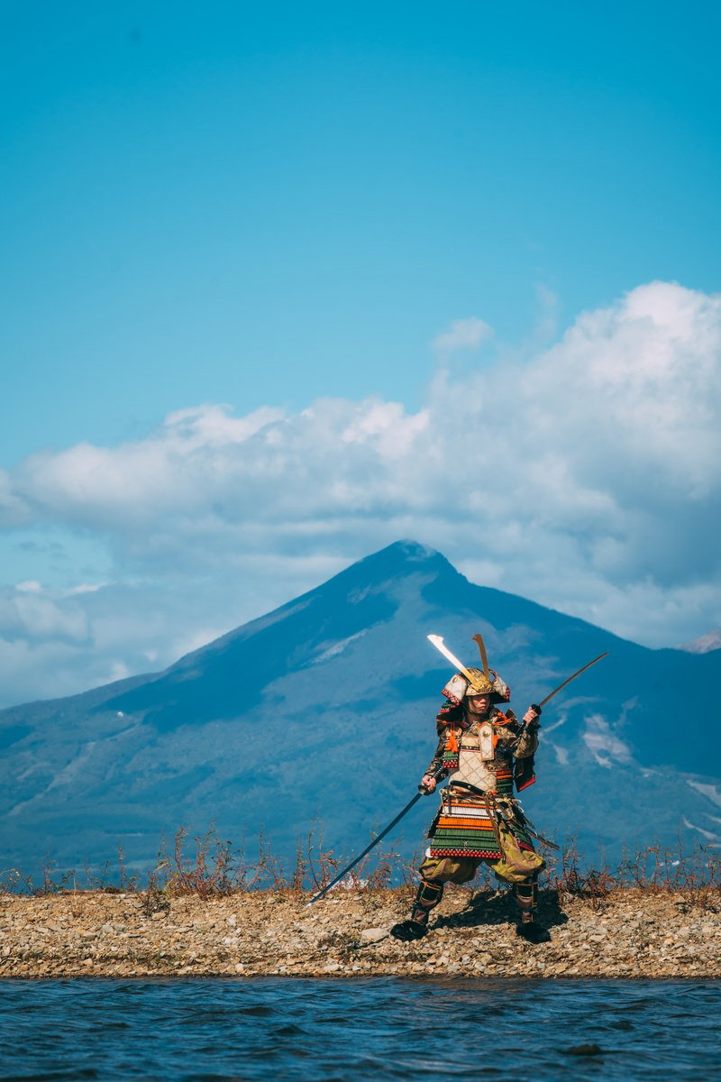 磐梯山を背に猪苗代湖の中州で二刀流をキメる大鎧武士の写真素材