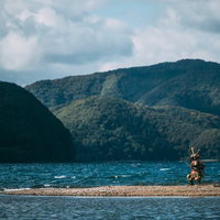 川の中州で刀を振り回す大鎧を身にまとった侍の戦闘シーンの写真