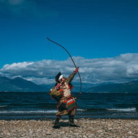 空に向かって大弓を放つ侍、中州の海岸で矢を射るの写真