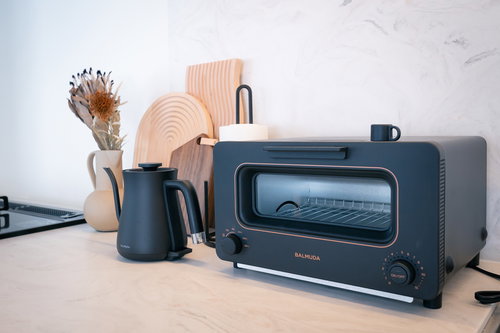 キッチンカウンターに置かれたグレーのトースターと茶色のポッド