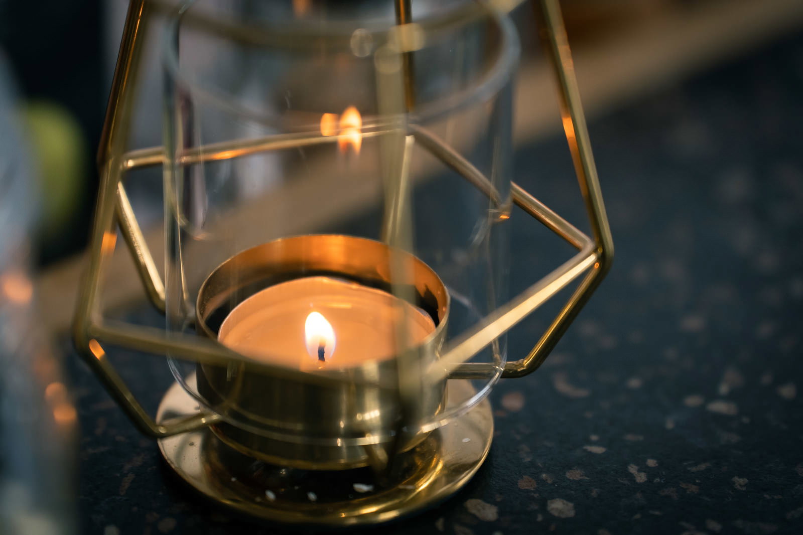 透明なガラス製の幾何学模様キャンドルホルダーに火が灯っている