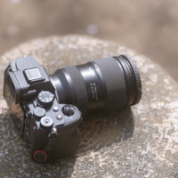 石の上に置かれたミラーレスカメラとレンズ機材の写真