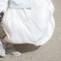 カメラを持ち、ひらめくスカートの裾を撮影する女性の写真