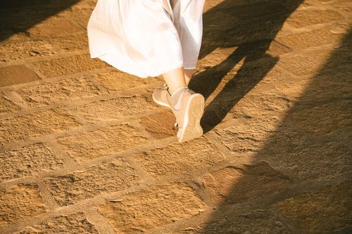 夕日に照らされた女性の歩くスニーカーの裏