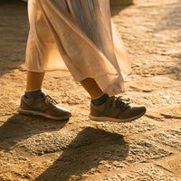 夕日に照らされる女性の足元とスニーカーの影の写真
