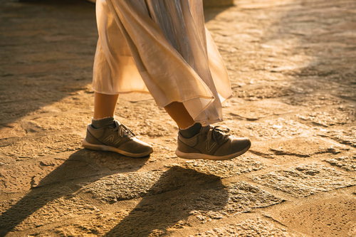 夕日に照らされる女性の足元とスニーカーの影