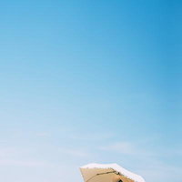 青空の下、ベージュの日傘を差す女子、展望デッキでのポートレートの写真