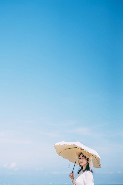 青空の下、ベージュの日傘を差す女子、展望デッキでのポートレート