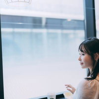 海ほたるの休憩所で窓辺に立つ黒髪の女性がベージュニットで一息の写真