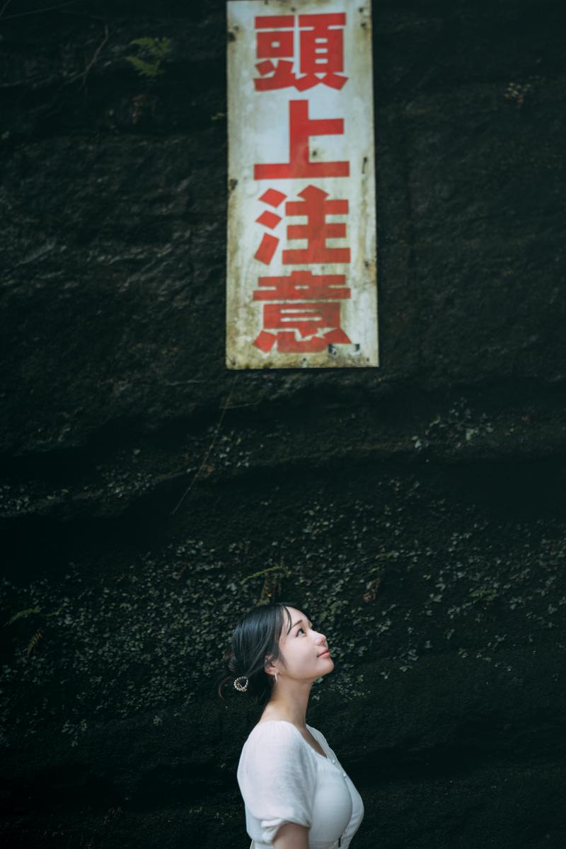 緑苔むしたトンネルの天井を見上げる、白いシャツ姿の女性［モデル：茜さや］