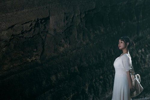 古い切通しを散策する観光女子、石壁に囲まれた薄暗い通路を歩く