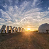 夕陽に照らされるMIYAKOの文字とドーム型テントの風景の写真