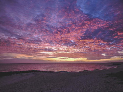 宮古島の砂浜で見る夕景 水平線に広がるグラデーション空