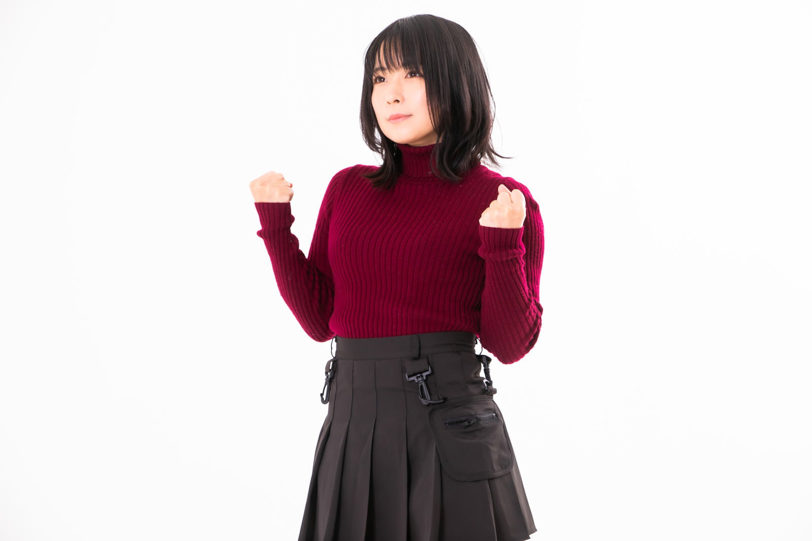 赤いニットを着た女性がガッツポーズをしている様子［モデル：にゃるる］