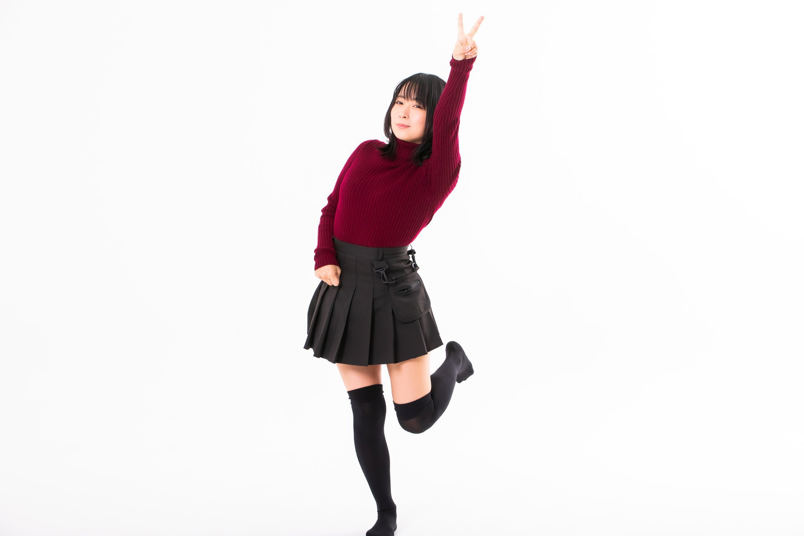 ブイサインを高く掲げるエンジ色のニット姿の女性［モデル：にゃるる］