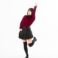 ブイサインを高く掲げるエンジ色ニット姿の女性の写真