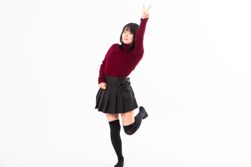 ブイサインを高く掲げるエンジ色ニット姿の女性