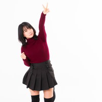 赤いニット姿で高々とピースサインする女性の写真