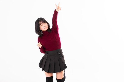 赤いニット姿で高々とピースサインする女性