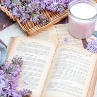 読みかけの洋書とライラックの花、ピンクのキャンドルの写真