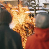 雪景色の中で行われる年始のお焚き上げを見守る人々の写真
