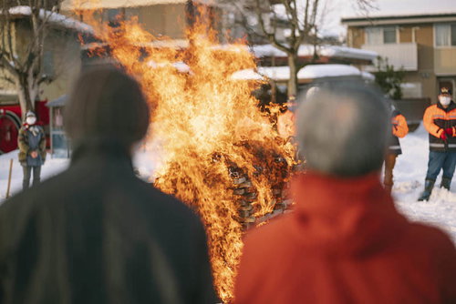 雪景色の中で行われる年始のお焚き上げを見守る人々