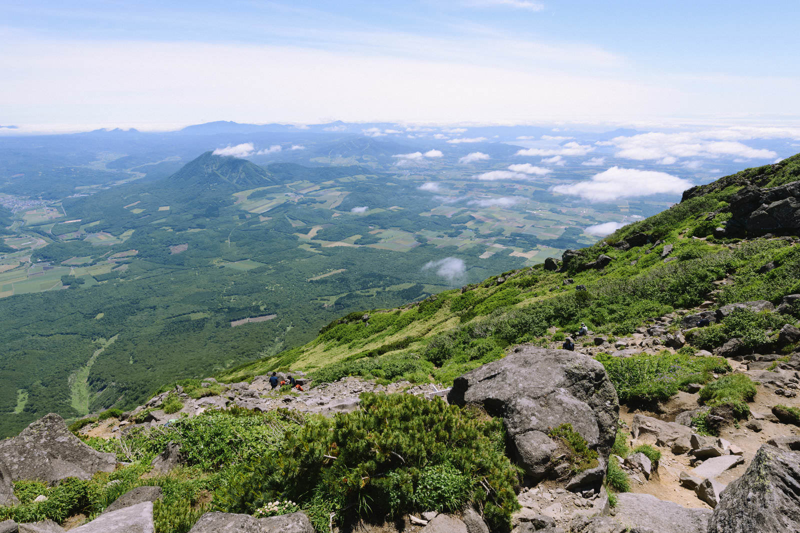 羊蹄山山頂の岩場から見下ろす尻別岳と緑の田園風景