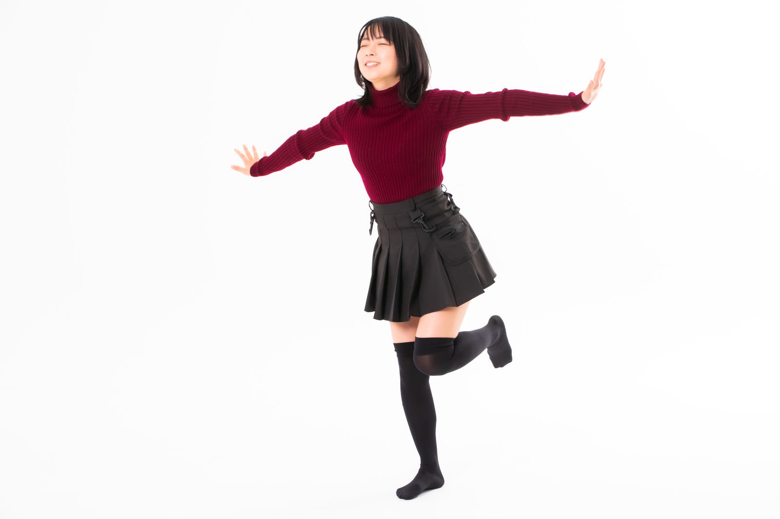 両腕を広げて片足立ちでバランスを取る赤いトップスの女性［モデル：にゃるる］