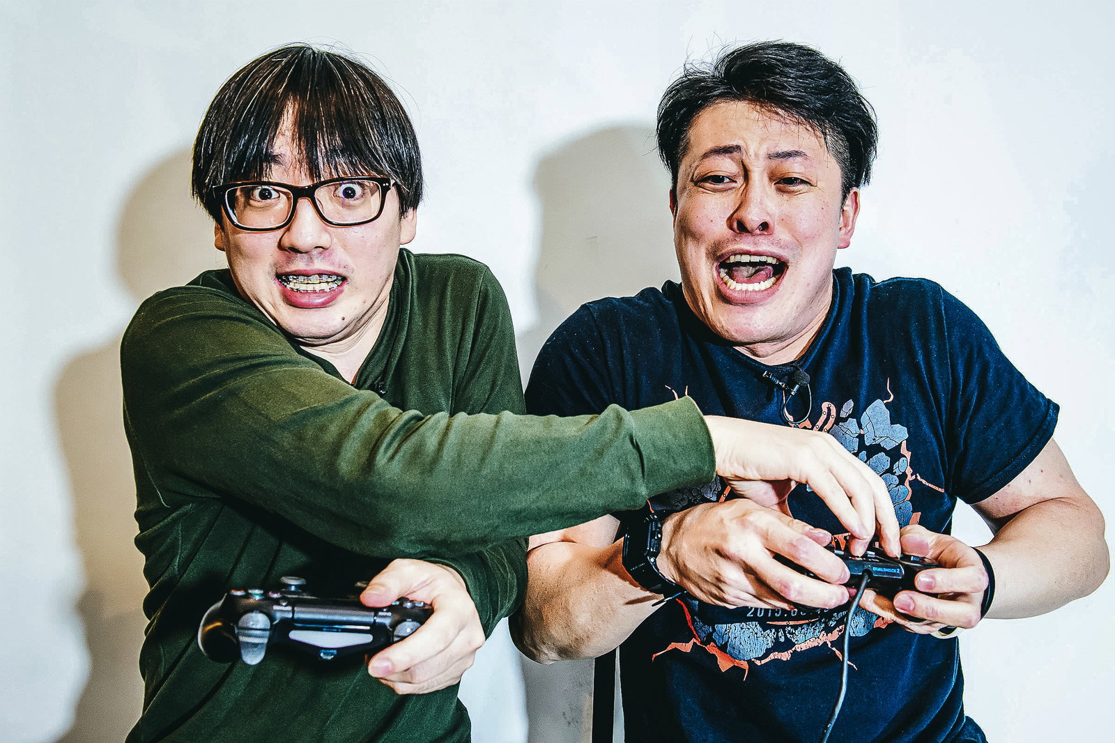 ゲームのコントローラーを引っ張られて妨害される眼鏡をかけた男性［モデル：モデルリリース］