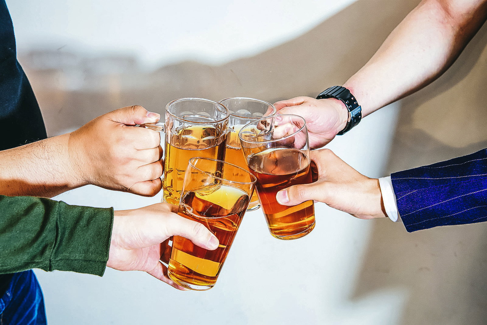 琥珀色のお酒が入ったグラスで乾杯する男性たちの手元