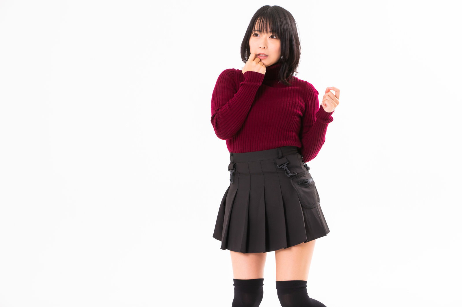 赤いセーターを着た女性が顎に手を当てて驚いた表情をしている［モデル：にゃるる］