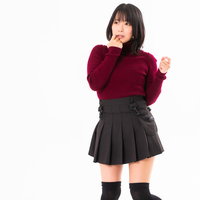 顎に手をあてて動揺する女性のポーズ、赤いセーター姿の写真