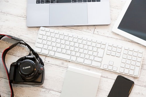 白いデスクに置かれたキーボードとミラーレスカメラ